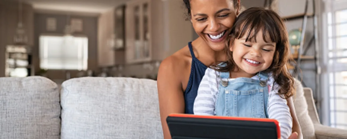 Mere et fillette souriantes devant une tablette