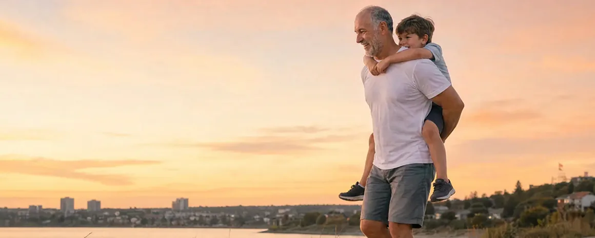 Homme portant un enfant sur son dos au bord de l eau au coucher du soleil
